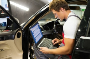 Serviceman making car diagnostics with laptop in a workshop
